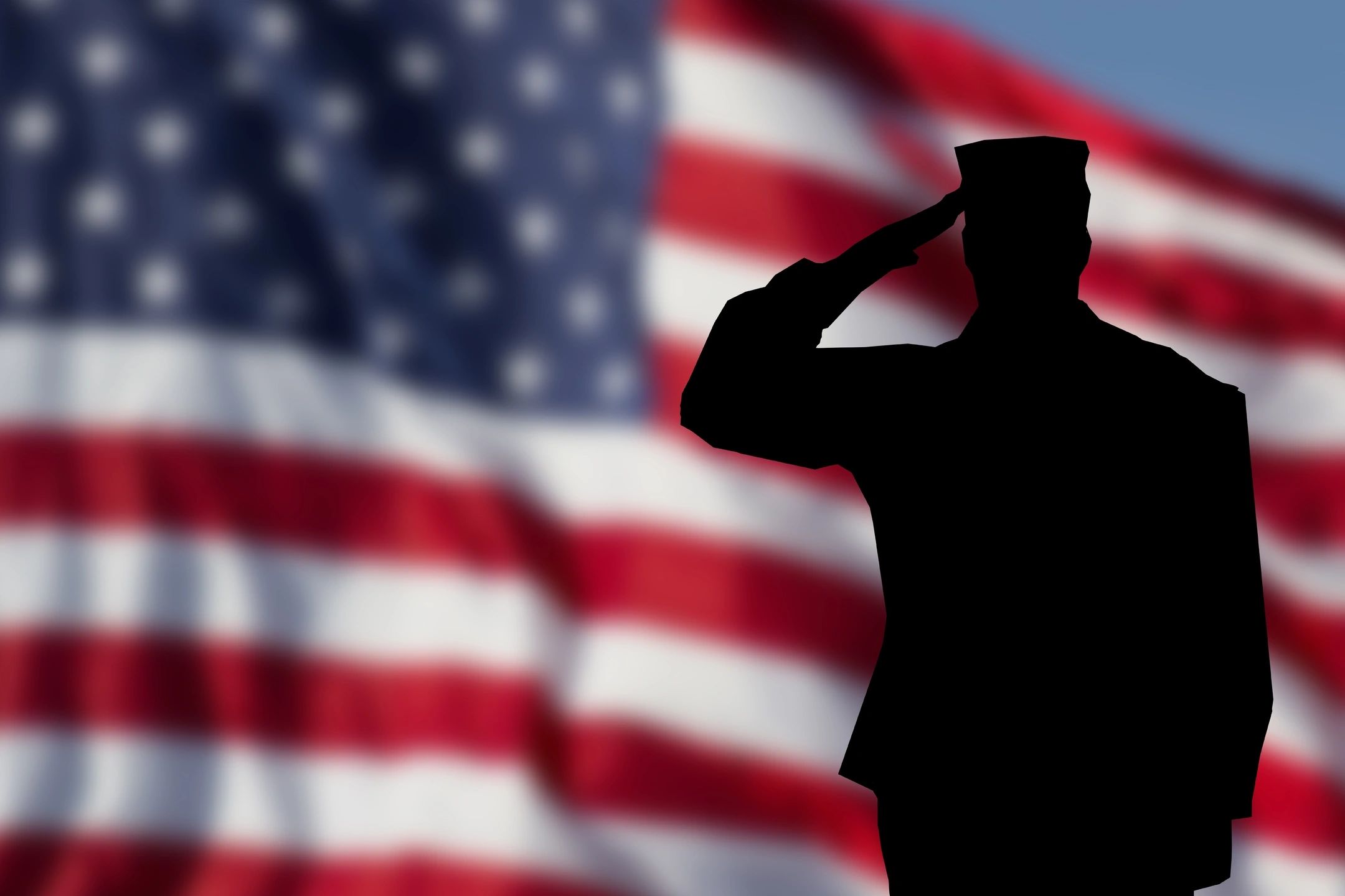 An image of an American flag with the silhouette of a veteran saluting in front.