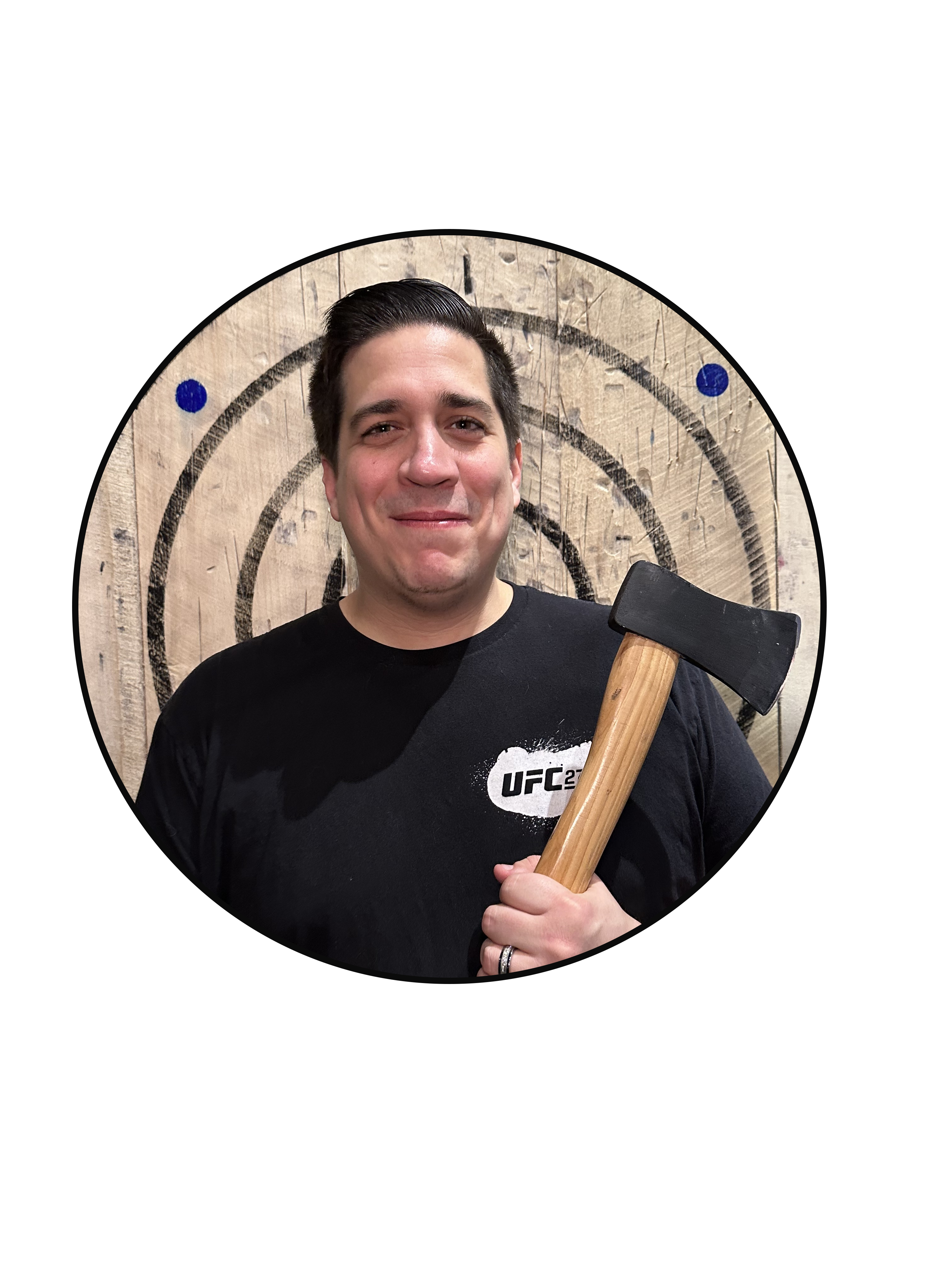 A happy man standing in front of a wooden target holding a throwing axe